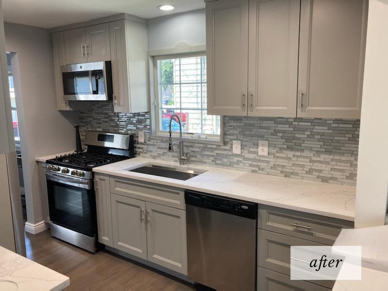 A kitchen redesign after shot with modern stainless stee appliances, white cabinets and countertop and a gray and white glass tile backsplash.