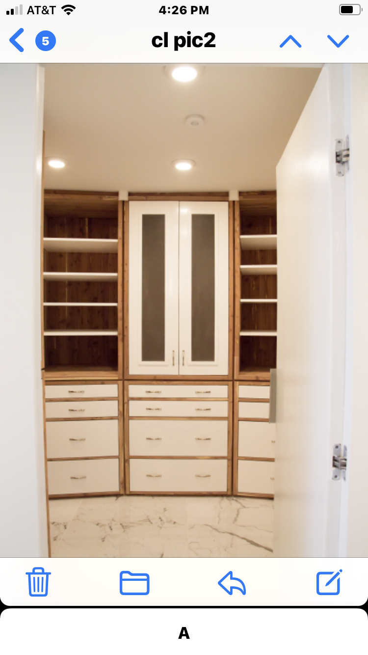 A white and light brown walk-in closet with 2 cabinets, open shelves and pull out drawers.