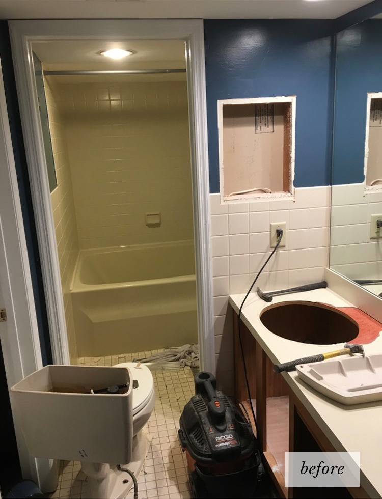 An old style bathroom with a mustard yellow bathtub and outdated tile and cabinets under construction.