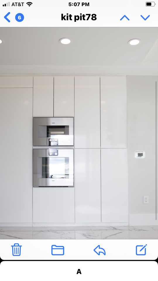 A clean and modern white cabinet system surrounds a stainless steel microwave and oven combo.