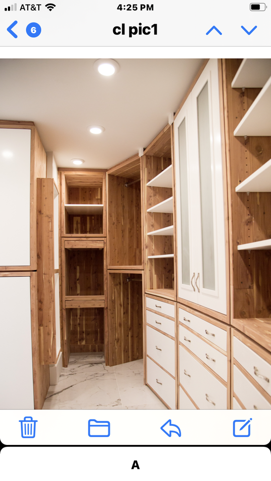 A light brown and white walk-in closet with plenty of storage shelves and drawers.