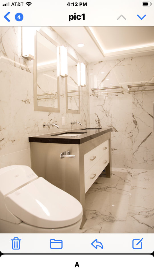 All white and gray marbled bathroom with a stainless steel and black double sink vanity and a modern white and sleek toilet.