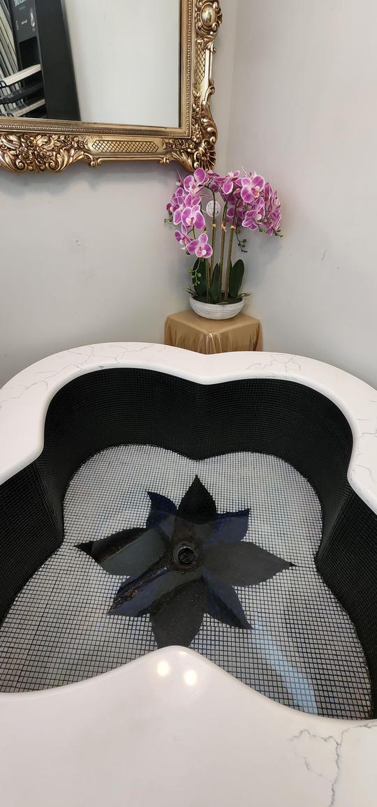 A close-up shot of the inside of an adorned black and blue glistening tiled bathtub.