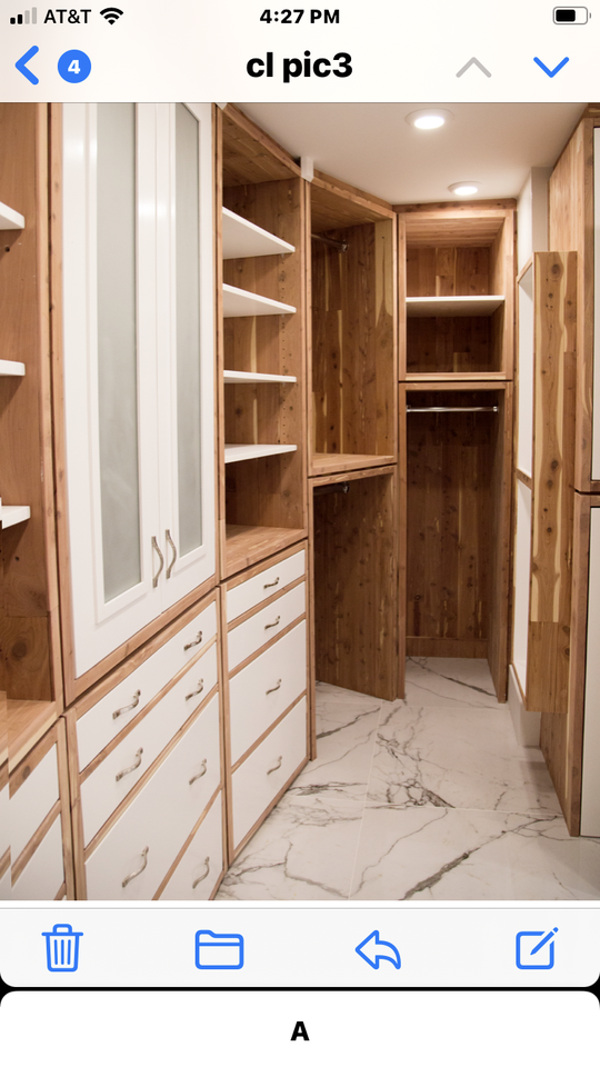 A light brown wood and white walk-in closet with a marbled floor equipped with open shelves, drawers and cabinets.