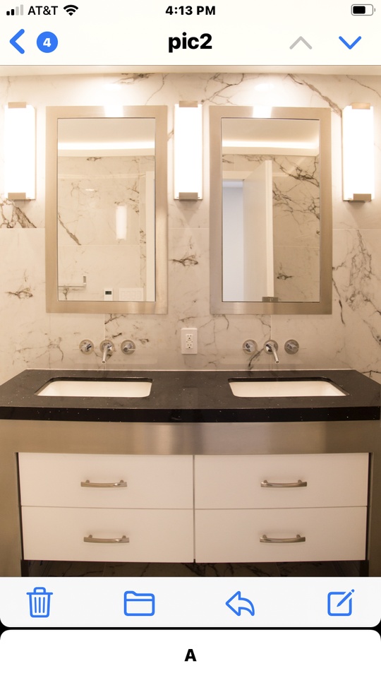 A white and gray marble tile bathroom wall with a stainless steel and black double sink vanity with 2 vertical mirrors.