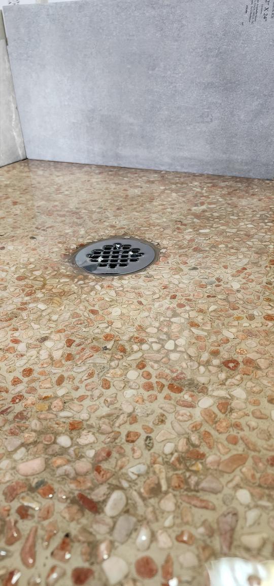 A close-up of a shower base with pebble flooring.